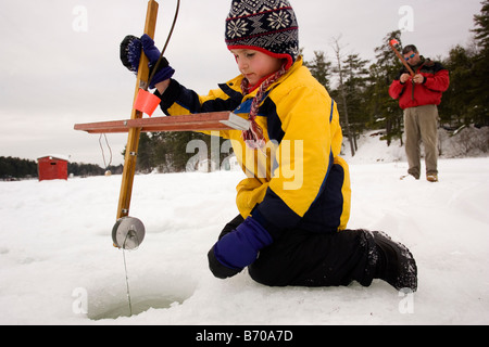 Les chèques d'un garçon, tandis que les pièges de la pêche sur glace sur le lac du Maine dans le Nord Waterboro, Maine. Banque D'Images