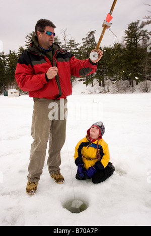 Un homme et un enfant vérifier les pièges, tandis que la pêche sur glace sur le lac du Maine dans le Nord Waterboro, Maine. Banque D'Images