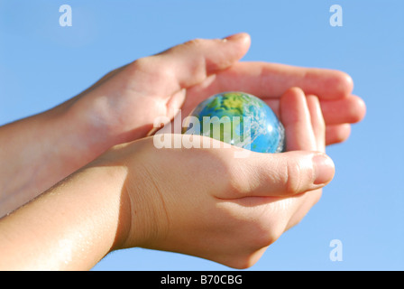 Enfant tenant un globe dans la main sur fond bleu Banque D'Images