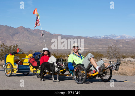 Un homme et une femme leur pédale vélo tandem avec leur chien le long de côte sur une route du désert de Mojave en dehors de Randsburg CA Banque D'Images