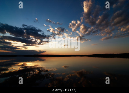 Magnifique coucher de soleil par lac calme avec des nuages contre l'assombrissement du ciel bleu, Asikkala, Finlande Banque D'Images