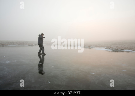 Un marcheur sur un tarn gelé près du sommet d'Caudale Moor dans le Lake District UK Banque D'Images