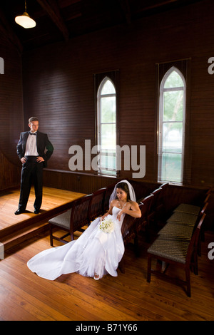 L'interracial jeunes mariés posant en église en bois sur le jour du mariage Banque D'Images