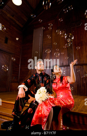 Jeune couple portant des vêtements traditionnels asiatiques assis à l'église autel Banque D'Images