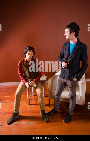 Portrait de deux jeunes hommes élégants souriants et boire Banque D'Images
