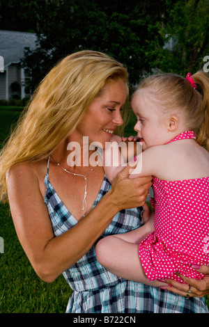 Mère tenant tout-petit avec le syndrome in backyard Banque D'Images