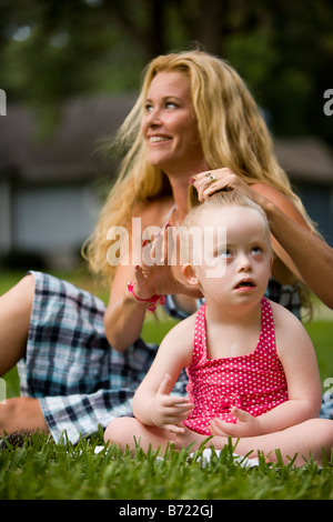 Mère peigner les cheveux de sa fille avec le syndrome de Down Banque D'Images