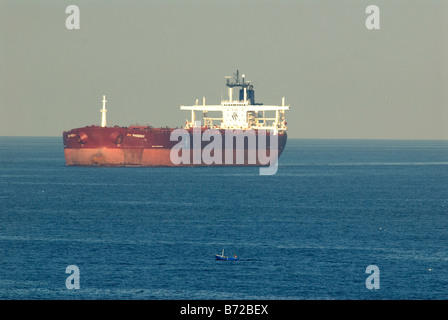 Super tanker ancrée en Méditerranée avec petit bateau de pêche ouvert en premier plan Banque D'Images