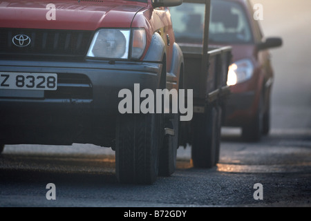 Véhicule 4x4 avec remorque suivie par voiture avec phares sur matin brumeux road County Down Irlande du Nord UK Banque D'Images