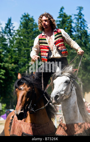 Image d'un Gypsy man riding deux chevaux en même temps debout avec un pied sur chaque cheval s dos Banque D'Images