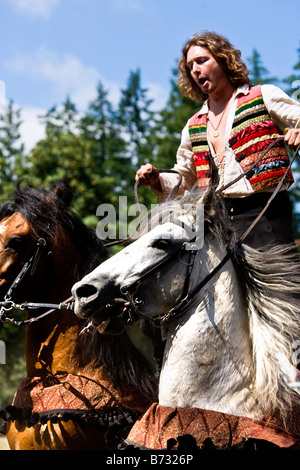 Image d'un Gypsy man riding deux chevaux en même temps debout avec un pied sur l'arrière de chaque cheval Banque D'Images