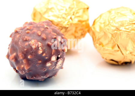 Sphère de chocolat gros plan avec les écrous à l'arrière-plan flou artistique wraped or Banque D'Images