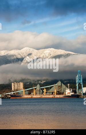 D'un cargo dans le port de Vancouver en face de montagnes couvertes de neige avec des nuages blancs et un ciel bleu. Banque D'Images