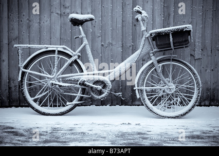 La British Royal mail postal delivery location appuyé contre une clôture sur un des hivers enneigés matin. Banque D'Images