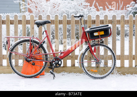 La British Royal mail postal delivery location appuyé contre une clôture sur un des hivers enneigés matin. Banque D'Images