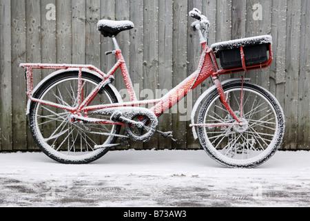 La British Royal mail postal delivery location appuyé contre une clôture sur un des hivers enneigés matin Banque D'Images