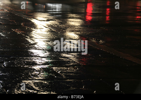 Route mouillée vide avec des lumières dans la ville la nuit Banque D'Images