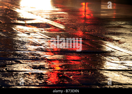 Route mouillée vide avec des lumières dans la ville la nuit Banque D'Images