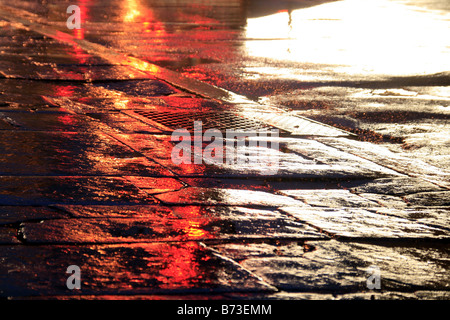 Route mouillée vide avec des lumières dans la ville la nuit Banque D'Images