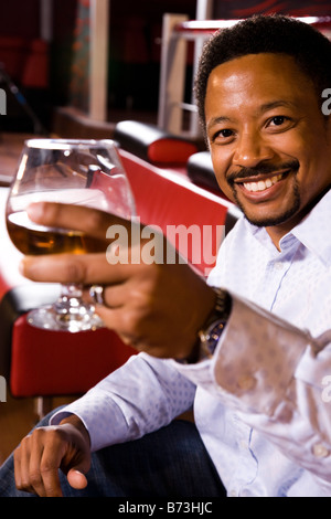 Portrait of young African American man verre de brandy sensibilisation at nightclub Banque D'Images
