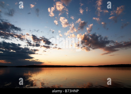 Magnifique coucher de soleil par lac calme avec des nuages contre l'assombrissement du ciel bleu, Asikkala, Finlande Banque D'Images