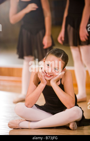 Happy young ballerina sitting on floor dans un studio de danse Banque D'Images