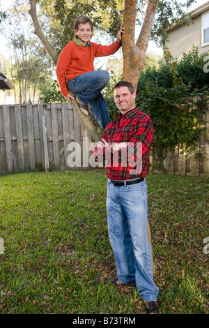 Heureux père et fils posant à côté de tree in backyard Banque D'Images