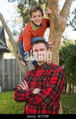 Heureux père et fils posant à côté de tree in backyard Banque D'Images