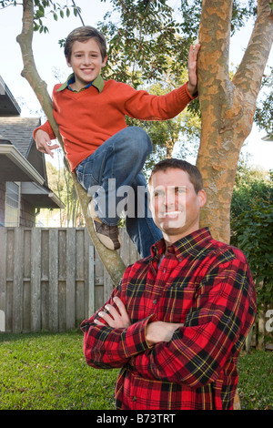 Heureux père et fils posant à côté de tree in backyard Banque D'Images