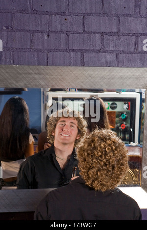 Jeune homme aux cheveux bouclés en se regardant dans le miroir Banque D'Images