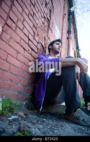 Jeune homme à nouveau penchée ruelle brick wall Banque D'Images