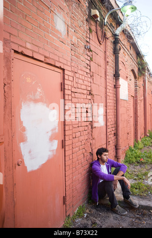 Jeune homme à nouveau penchée ruelle brick wall Banque D'Images