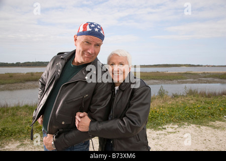 Happy senior couple in biker jackets standing on dirt road Banque D'Images