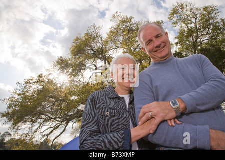 Romantic couple standing arm in arm à l'extérieur dans le parc Banque D'Images