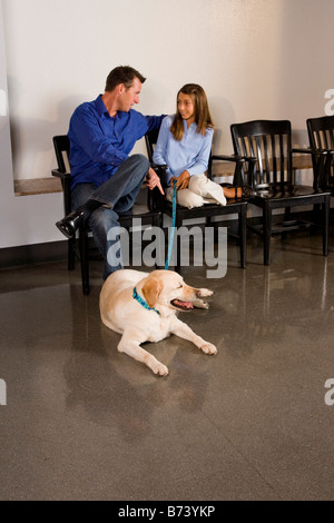 Père et fille dans la salle d'attente de clinique vétérinaire avec chien Banque D'Images