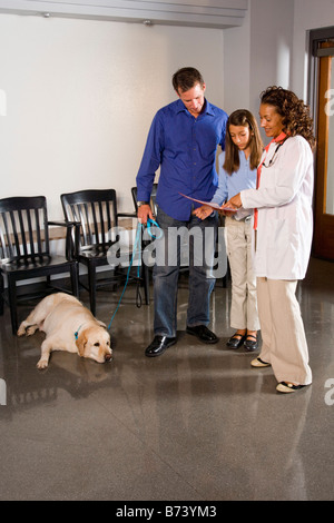 Vétérinaire avec la famille et le chien en clinique vétérinaire Banque D'Images