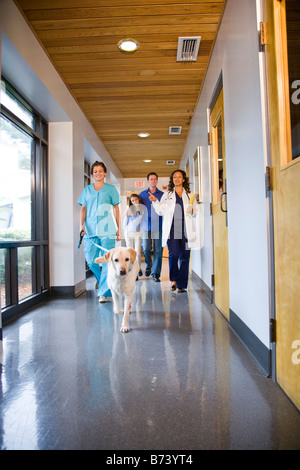 Balades en famille et vétérinaire chien vers le bas du couloir de la clinique Banque D'Images