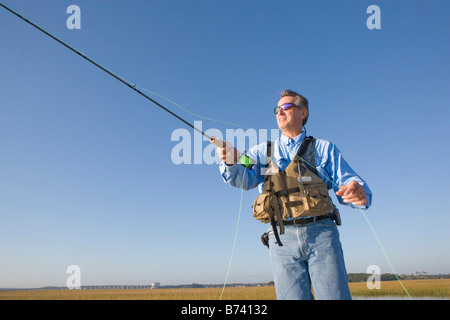 L'adulte l'Homme à lunettes casting canne à pêche en rivière Banque D'Images