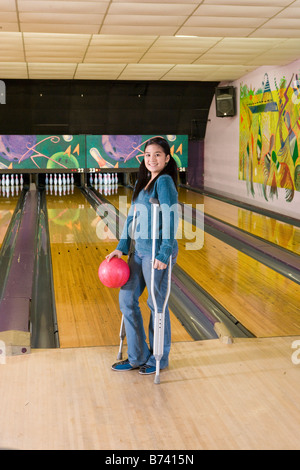 Asian teenage Girl standing sur des béquilles et de bowling Banque D'Images