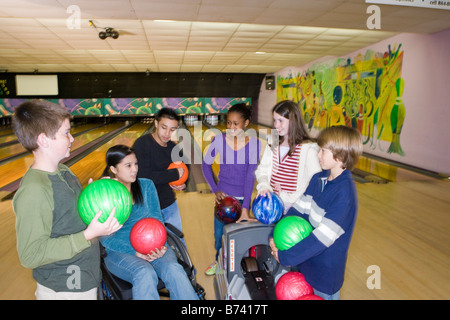 D'interpolations de multi-raciale dans bowling avec girl in wheelchair Banque D'Images