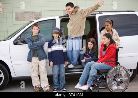 Les enfants multi-ethnique traînant en minibus dans un terrain de stationnement, girl in wheelchair Banque D'Images