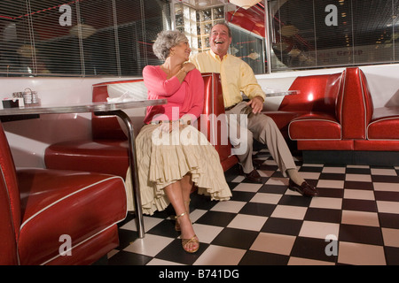 Senior couple sitting dans les cabines de vieux diner laughing Banque D'Images