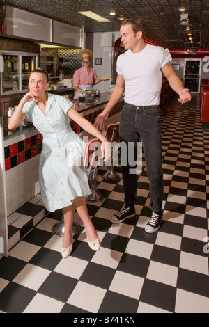 Jeune femme assise au comptoir de salle à manger, petit ami ignorant style années 50 Banque D'Images