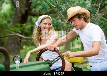 Jolie jeune femme sur le tracteur avec man in cowboy hat Banque D'Images
