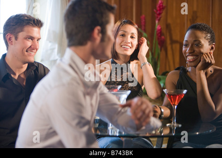 Les amis des jeunes adultes la conversation à table dans un restaurant having cocktails Banque D'Images