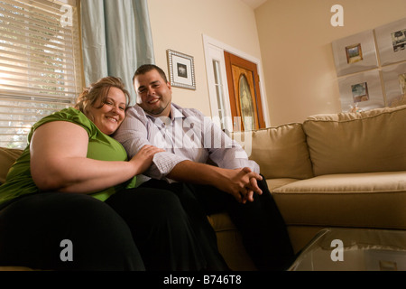 L'excès de couple sitting on sofa in living room Banque D'Images