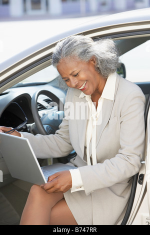 African businesswoman using laptop in car Banque D'Images