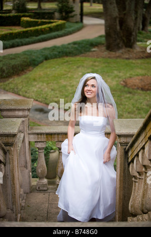 Heureux jeune épouse en robe de mariage en montant un escalier extérieur Banque D'Images