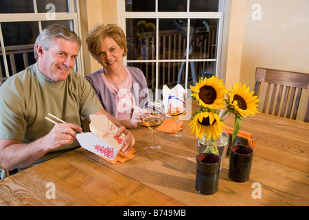 Middle-aged couple eating Chinese emporter ensemble dans la salle à manger Banque D'Images