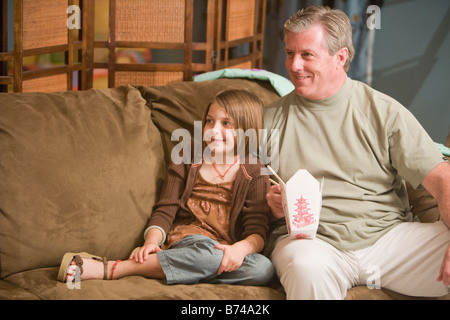 Le père et l'enfant assis sur le divan à regarder la télévision pour emporter l'alimentation Banque D'Images